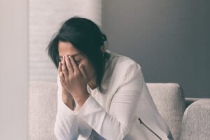 A woman with dark hair holding her nose in a distressed manner. Trauma therapy in Portland, OR offers a safe space for individuals to heal. Get started with our therapists today.