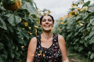 A woman walking through a sunflower field & smiling bright. Anxiety treatment in Portland, OR can help you develop tools to navigate analysis paralysis. Start your healing today with our anxiety therapists.