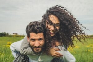 A happy woman riding on a man's back while smiling. Representing how anxiety therapy in Portland, OR can help you with relationship anxiety & communication. Get started with an anxiety therapist today!