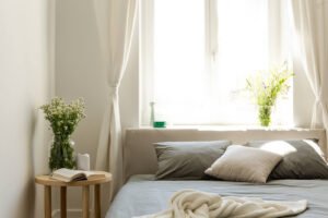 A well lit bedroom with fresh white flowers, grey bedding & white curtains. If you want to learn more information on anxiety & sleep, reach out to us today. Our anxiety therapy in Portland, OR can help you sleep better!