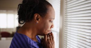 A woman resting her head on her chin while worrying, looking out the window. Our anxiety counseling in Portland, OR can help you with learning the connection between hormones & anxiety. Get started today!