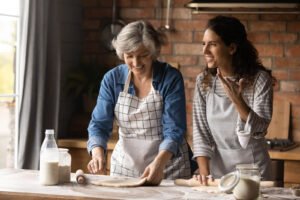 Two women rolling out dough together in the kitchen while having a conversation. If you're struggling with mood swings, brain fog & anxiety, reach out to us today. We offer anxiety counseling in Portland, OR to help!