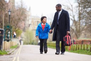 A professional father walking his son to school carrying a red backpack. Our anxiety counseling in Portland, OR can help children with social anxiety. Support your child today!