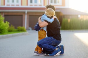 A father bending down hugging his son before school. Building a good-bye ritual with your child can help with separation anxiety. Learn more in child anxiety counseling in Portland, OR. 