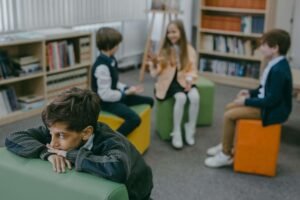 An upset child sitting away from other child during school. Get started with our anxiety counseling in Portland, OR to support your child's well-being. Reach out to us today to get started. 