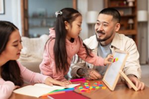 A multicultural family sitting together at the table doing a school activity. Child anxiety counseling in Portland, OR is here to support your family. Reach out today to get paired with a therapist. 