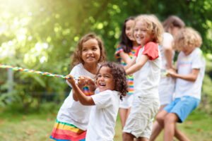 A group of diverse children playing tug of war outside. Representing how anxiety therapy in Portland, OR can help your child with anxiety & self-esteem. Reach out today!