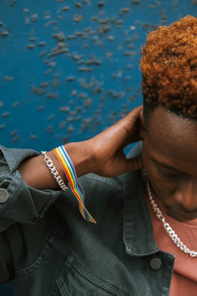 Person wearing a rainbow pride ribbon bracelet and silver chain, representing LGBTQIA+ identity and support, symbolizing the affirming therapy offered at Mindful Mental and Behavioral Health PLLC in Portland, Oregon and Seattle, Washington.