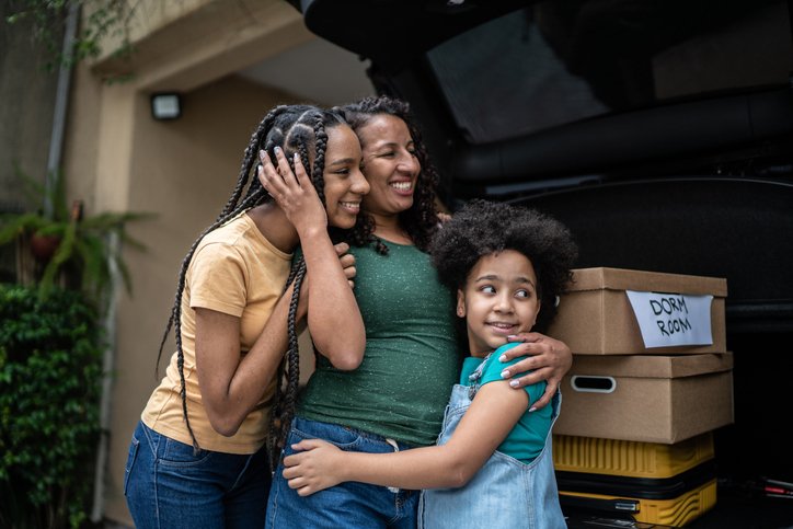 Family sharing an emotional hug during a college move in Portland Oregon, representing the support and stress of major life transitions.