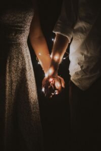 A couple holding hands with twinkle lights wrapped around their arms. Learn how trauma counseling in Portland, OR can help with trauma bonding & relationship anxiety. Get the personalized support you deserve today!