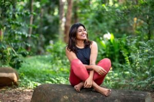 A happy woman sitting criss cross on a log outside. Trauma therapy in Portland, OR is here to support your healing journey. Reach out today to begin!