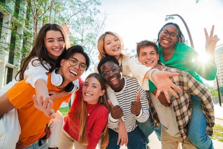Group of diverse teenagers smiling and supporting each other outdoors, representing youth mental health services and positive peer connection.